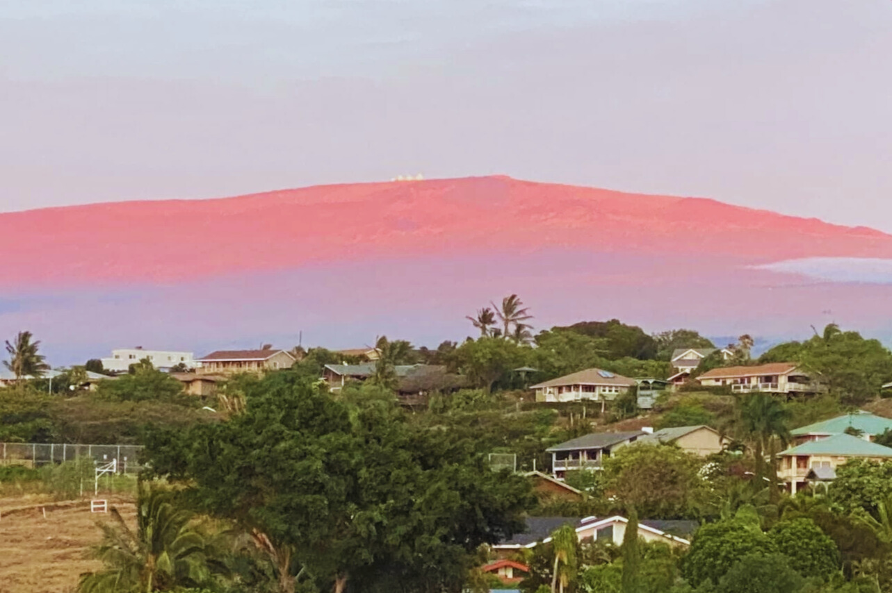 夕焼けに染まるマウナケア山と天文台を望む、ハワイ島ワイコロアビレッジの景色。