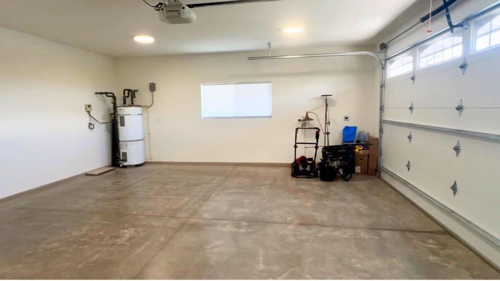 ハワイ島ワイコロアビレッジの戸建て住宅の2台分ガレージ。広々としたコンクリート床と自動シャッター付きの明るいスペース。